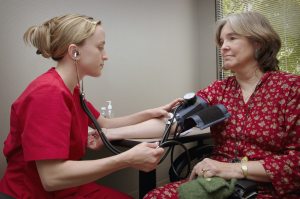 Woman having blood pressure measured by a physician's assistant